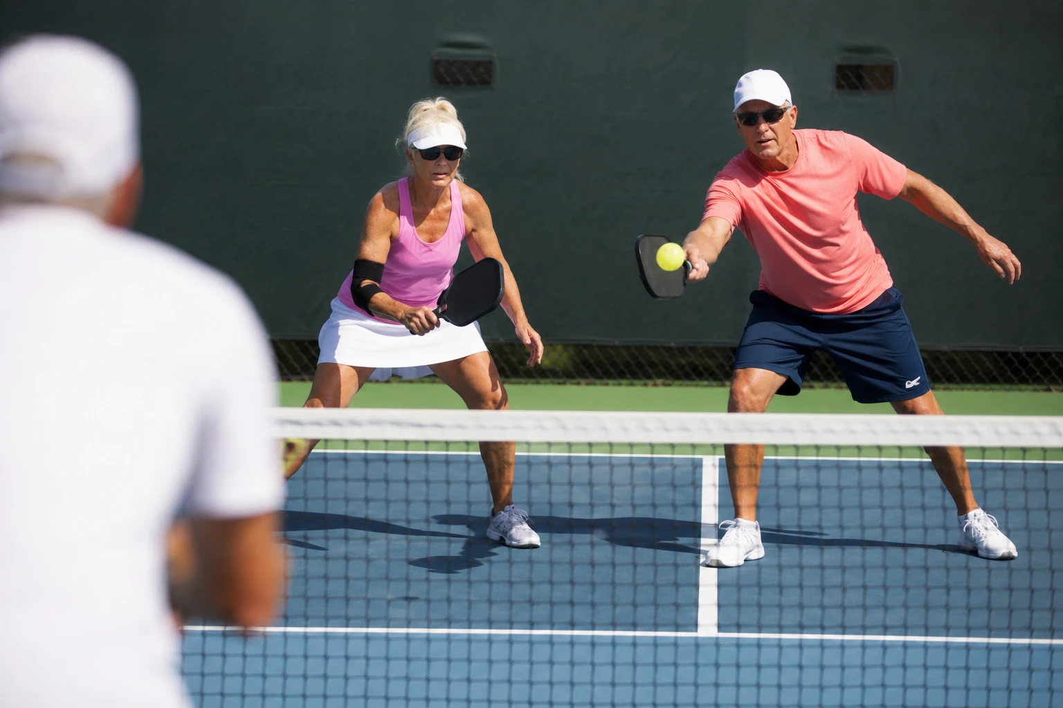 Two players at the net in a doubles pickleball match on an outdoor court